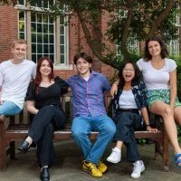 2024/25 Officer Trustees sitting on a bench outside in Beit Quad. They are smiling and seated together.